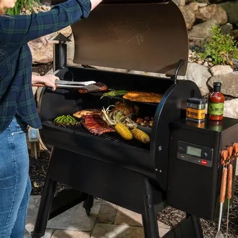 A man and woman standing next to an outdoor grill.