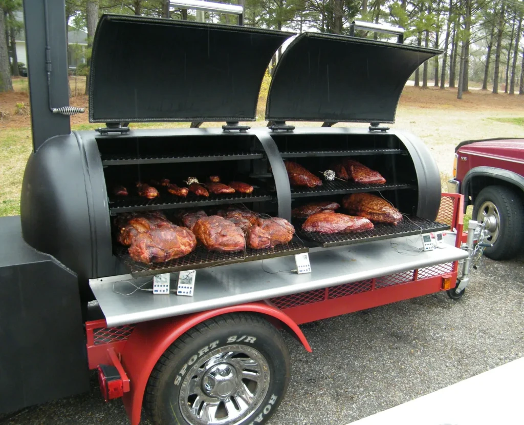 A man and woman standing next to an outdoor grill.